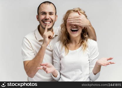 man laughing covers woman eyes