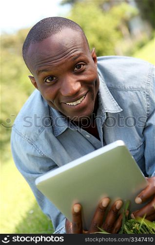 Man laying down in park with electronic tablet