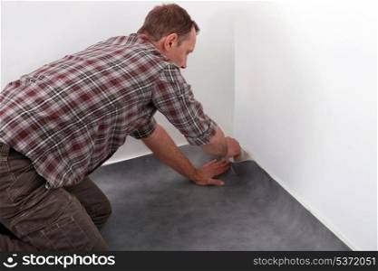 Man laying new carpet in room