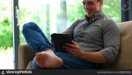 man laying on couch in luxuary villa and using tablet