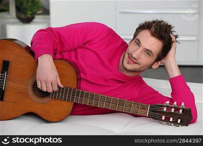 Man laying on sofa with acoustic guitar
