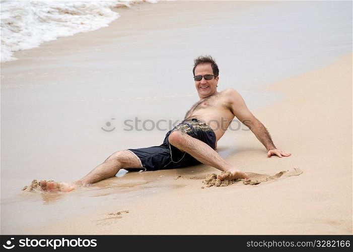 Man laying on the sand along shoreline in Bali