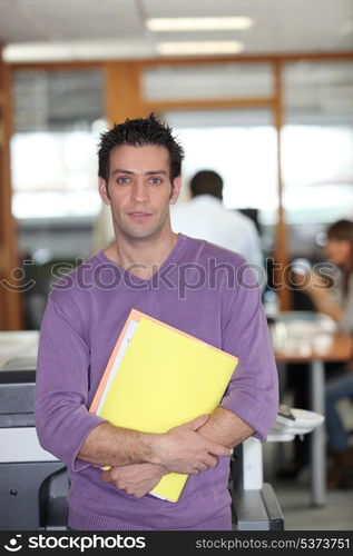 Man leaning against a photocopier with a armful of files