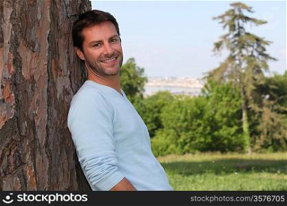 Man leaning against a tree
