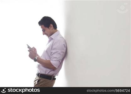 Man leaning against a wall reading an sms
