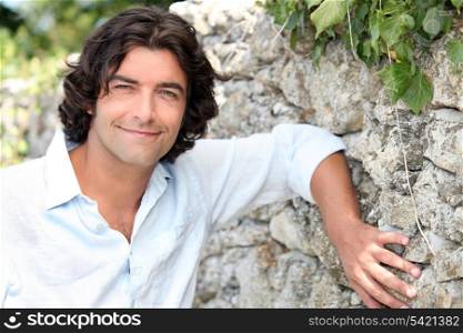 Man leaning against stone wall