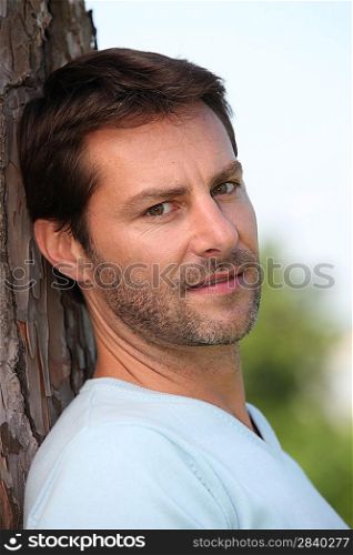 Man leaning against tree