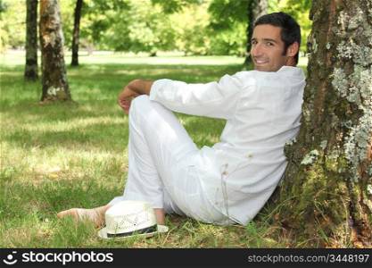 Man leaning against tree