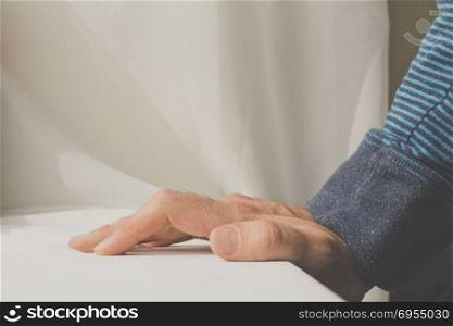 Man leaning and puts his hands down on white cloth background.