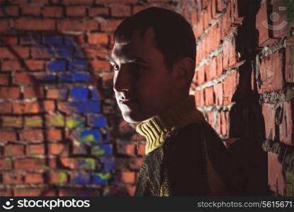 Man leaning on a brick wall in abandoned unfinished house