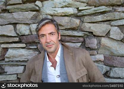 Man leaning on stone wall in countryside