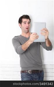 Man leaning on wall with electronic tablet
