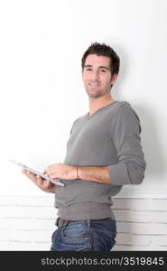 Man leaning on wall with electronic tablet