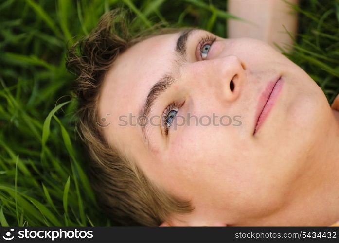 Man lie on the grass and look up. Shallow DOF. Outdoor portrait