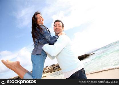 Man lifting his girlfriend up in arms by the beach
