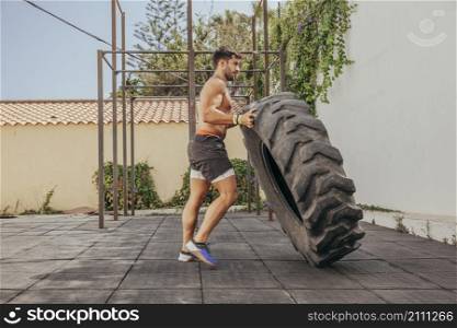 man lifting tractor wheel