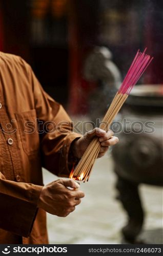 man lighting bundle incense temple