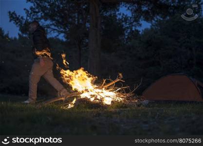 Man lights a fire in the fireplace in nature at night.