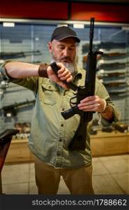 Man loads automatic rifle in gun store. Weapon shop interior, ammo and ammunition assortment, firearms choice, shooting hobby and lifestyle, self protection. Man loads automatic rifle in gun store