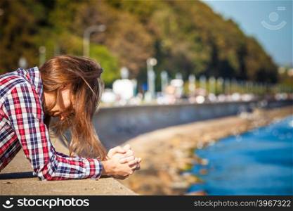 Man long hair alone on sea shore, lost in thought, is concerned and stressed about events in his life. Unemployment depression concept