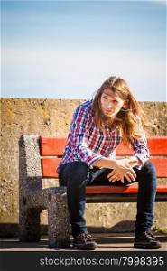 Man long hair sitting on bench outdoor. Man bearded long hair wearing plaid shirt casual style relaxing outdoor at summer sunny windy day sitting on bench