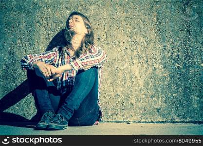 Man long haired sitting alone sad on grunge wall. Man bearded long hair sitting sad alone by grunge wall outdoor. Unemployment depression or sadness concept.