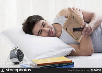 Man looking at a picture frame in bed