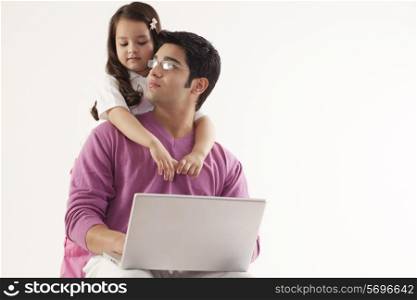 Man looking at daughter while using laptop