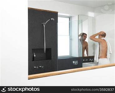 Man looking at himself in bathroom mirror half-length