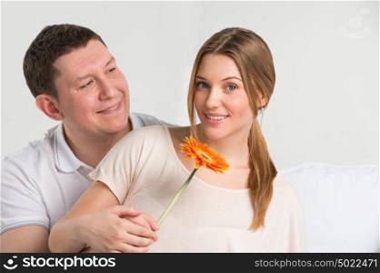 Man looking at his beautiful girlfriend and giving her a flower at home