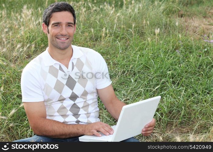 Man looking at his laptop in a field