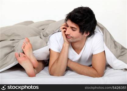 Man looking at his partner&rsquo;s feet in bed