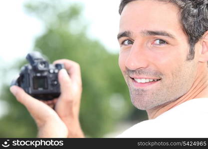 Man looking at the back of a digital camera