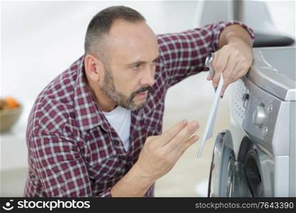 man looking at washing machine and holding instructions