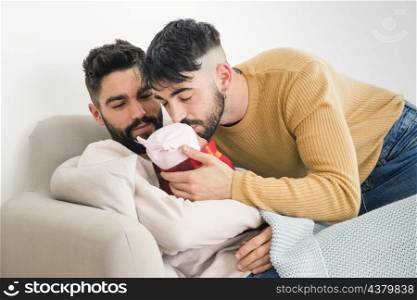 man looking his boyfriend kissing their sleeping baby