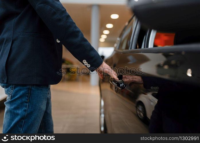 Man looking on transport interior in car dealership. Customer in new vehicle showroom, male person buying automobile, auto dealer business. Man looking on transport interior, car dealership