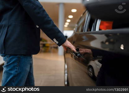 Man looking on transport interior in car dealership. Customer in new vehicle showroom, male person buying automobile, auto dealer business. Man looking on transport interior, car dealership