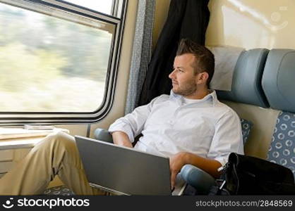 Man looking out the train window laptop commuter pensive journey
