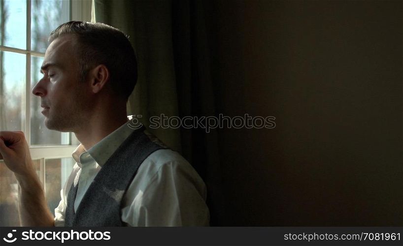 man looking out window from inside dark room