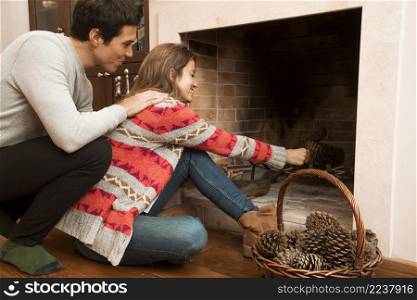 man looking young woman placing pinecone fireplace