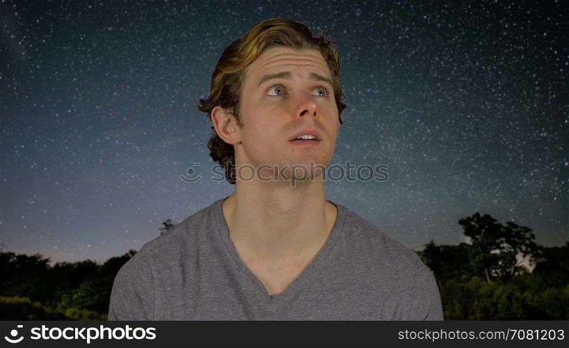 Man looks above head at night sky