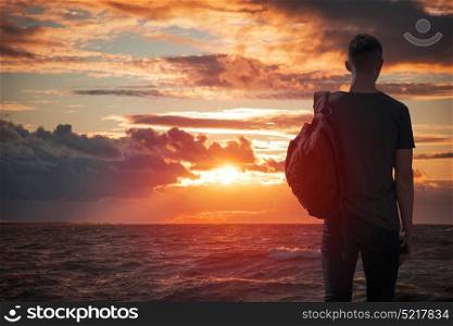 man looks at sunset by the sea