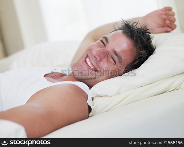 Man lying in bed laughing