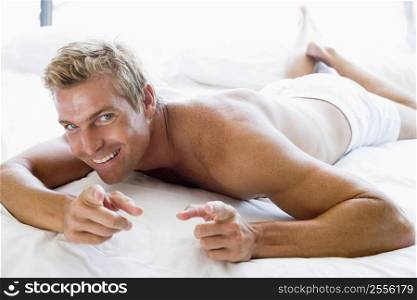 Man lying in bed pointing and smiling