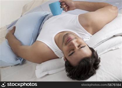 Man lying in bed with a cup of coffee