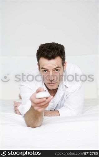 man lying on bed with remote controls