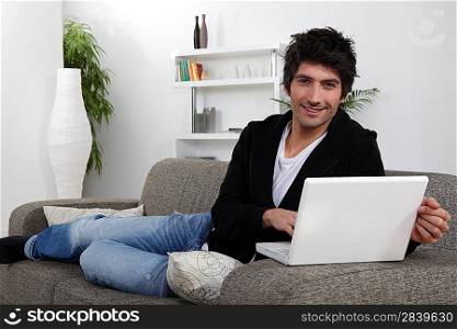 Man lying on sofa with computer