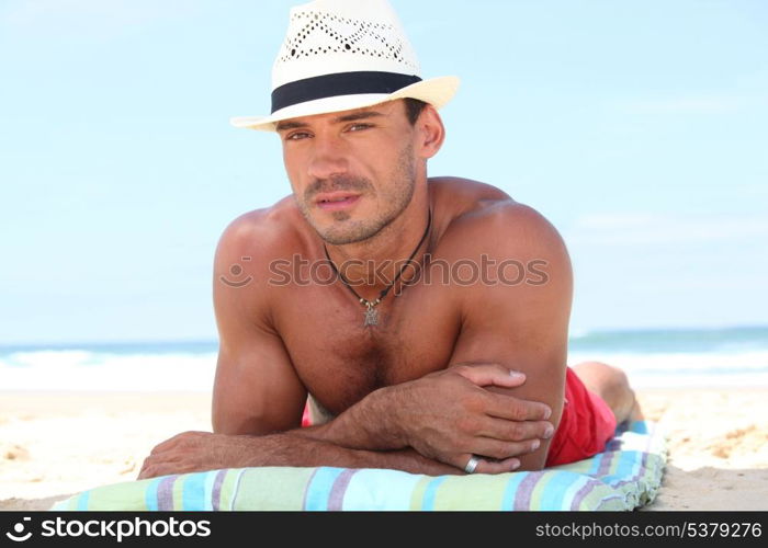 Man lying on the beach in a straw hat