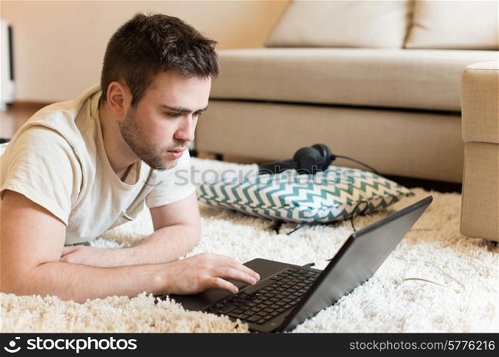 Man lying on the floor typing on laptop