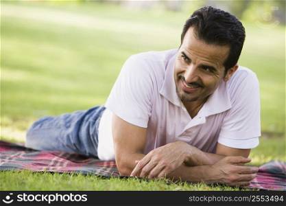 Man lying outdoors at park smiling (selective focus)